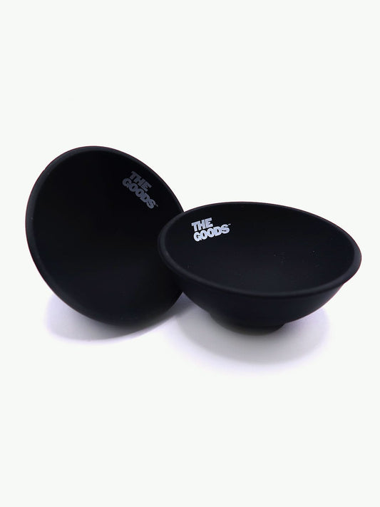Two The Goods Black Silicone Bowls by The Goods sit on white, ideal as portable rolling trays.