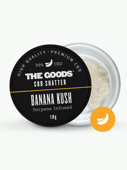 A small glass jar labeled “The Goods BANANA KUSH CBD ISOLATE SHATTER UK” with a banana icon, containing a pale crystalline substance infused with natural terpenes.