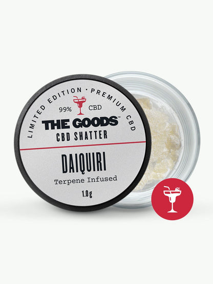 A small jar labeled “The Goods STRAWBERRY DAIQUIRI CBD ISOLATE SHATTER UK, Terpene Infused, 1.0g” with the lid off reveals a light yellow crystalline substance inspired by the flavor of strawberry daiquiri. This premium product showcases The Goods’ dedication to expertly crafted CBD extracts.